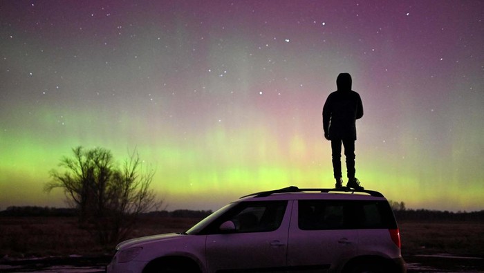 A person stands on a car while looking at Auroras, caused by a coronal mass ejection on the Sun, that illuminate the skies in the southwestern Siberian Omsk region, Russia November 6, 2023. REUTERS/Alexey Malgavko TPX IMAGES OF THE DAY