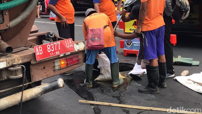 Petugas dari Dinas Pekerjaan Umum, Perumahan, dan Kawasan Pemukiman (PUPKP) membersihkan luberan minyak di utara Tugu Pal Putih Kota Jogja, Selasa (7/11/2023) pagi.