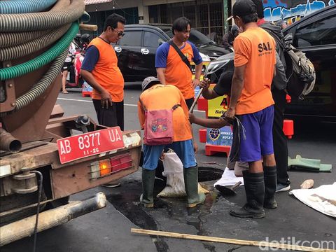 Petugas dari Dinas Pekerjaan Umum, Perumahan, dan Kawasan Pemukiman (PUPKP) membersihkan luberan minyak di utara Tugu Pal Putih Kota Jogja, Selasa (7/11/2023) pagi.