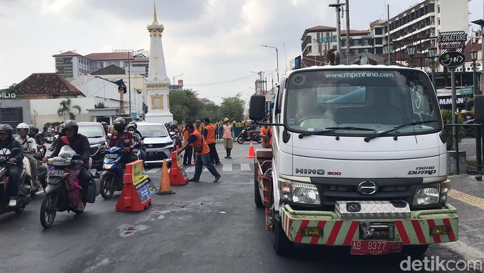 Petugas dari Dinas Pekerjaan Umum, Perumahan, dan Kawasan Pemukiman (PUPKP) membersihkan luberan minyak di utara Tugu Pal Putih Kota Jogja, Selasa (7/11/2023) pagi.