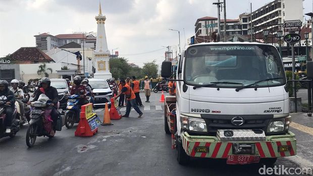Petugas dari Dinas Pekerjaan Umum, Perumahan, dan Kawasan Pemukiman (PUPKP) membersihkan luberan minyak di utara Tugu Pal Putih Kota Jogja, Selasa (7/11/2023) pagi.