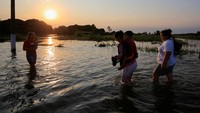 Sejumlah warga melintasi jalanan yang terendam banjir menuju lokasi pengungsian. 
