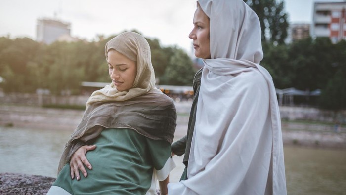 Cute and lovely pregnant Muslim woman and her Muslim friend, spending the time together on a city street.