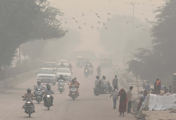 A man wearing face mask walks with his dog on a footpath amidst the morning smog in New Delhi, India, November 7, 2023.REUTERS/Anushree Fadnavis
