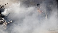 Petugas damkar menembus asap untuk menjinakkan api yang membakar rumah warga di kawasan Khan Younis, Jalur Gaza. Reuters/Mohammed Salem. 