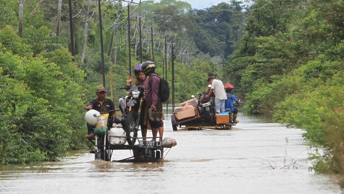 Sejumlah pengedara memanfaatkan jasa angkut untuk melintasi jalan yang terendam banjir di Desa Layung, Bubon, Aceh Barat, Aceh, Kamis (9/11/2023). Data BPBD Kabupaten Aceh Barat menyebutkan banjir karena tingginya intensitas hujan dan meluapnya sungai Krueng Woyla dan Krueng Meureubo tersebut mengakibatkan ratusan rumah warga dan puluhan hektar lahan pertanian terendam banjir dengan ketinggian air 30 cm hingga 110 cm. ANTARA FOTO/Syifa Yulinnas/wpa.