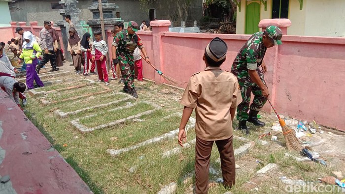 TNI Polri dan siswa SDN 2 Dukuh Tengah membersihkan taman makam pahlawan di desa setempat