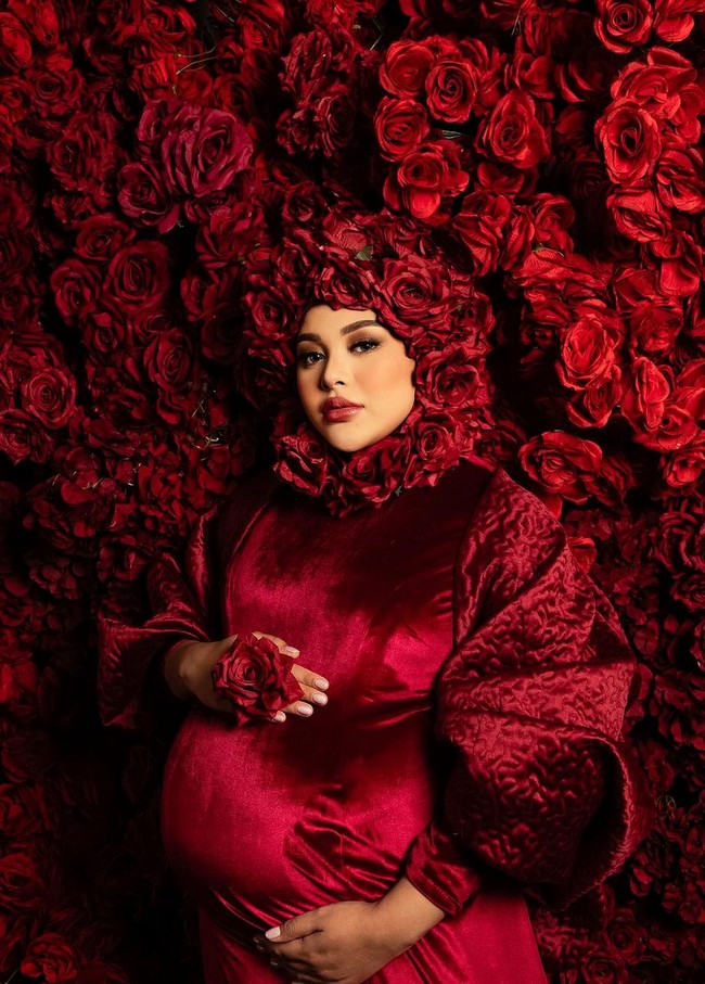 Hamil 9 bulan, Aurel tampil bak putri bunga, mengenakan gaun merah dengan latar belakang mawar. Hijabnya pun dihiasi mawar yang semakin memancarkan aura glamor. Foto: Instagram/@aurelie.hermansyah