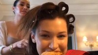 Tak hanya pizza, tapi Bella juga menyukai junk food lainnya. Seperti yang terlihat dalam momennya kali ini, ia menikmati burger dan kentang goreng. Foto: Instagram @bellahadid