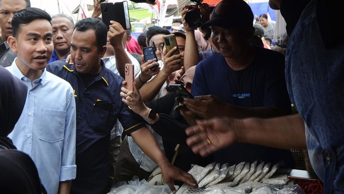 Sejumlah warga berebut untuk bersalaman dengan bakal calon wakil presiden dari Koalisi Indonesia Maju (KIM) Gibran Rakabuming Raka (tengah) saat safari politik di Pasar Natar, Lampung Selatan, Lampung, Sabtu (11/11/2023). Gibran melakukan safari politik di provinsi tersebut dengan mengunjungi sejumlah tempat guna menemui dan mendengar aspirasi pendukungnya.