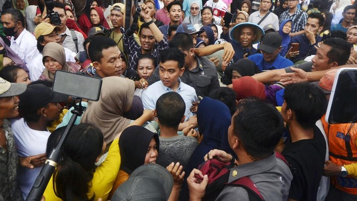 Sejumlah warga berebut untuk bersalaman dengan bakal calon wakil presiden dari Koalisi Indonesia Maju (KIM) Gibran Rakabuming Raka (tengah) saat safari politik di Pasar Natar, Lampung Selatan, Lampung, Sabtu (11/11/2023). Gibran melakukan safari politik di provinsi tersebut dengan mengunjungi sejumlah tempat guna menemui dan mendengar aspirasi pendukungnya.