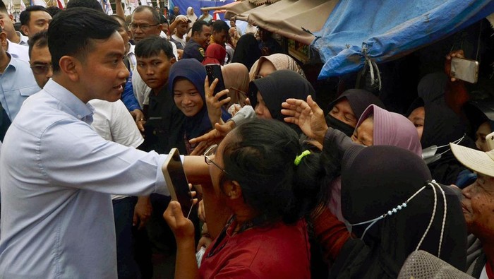 Sejumlah warga berebut untuk bersalaman dengan bakal calon wakil presiden dari Koalisi Indonesia Maju (KIM) Gibran Rakabuming Raka (tengah) saat safari politik di Pasar Natar, Lampung Selatan, Lampung, Sabtu (11/11/2023). Gibran melakukan safari politik di provinsi tersebut dengan mengunjungi sejumlah tempat guna menemui dan mendengar aspirasi pendukungnya.