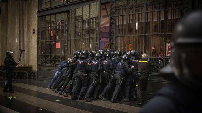 Momen Polisi Bentrok dengan Massa Pro-Palestina di Spanyol Police officers try to contain protesters trying to enter the train station in Barcelona, Spain, Satuday, Nov. 11, 2023. Antiriot police in northeastern Spain's Barcelona briefly clashed with about 2,000 pro-Palestinian protesters who stormed and occupied a commuter train station. The protesters were part of a group of many thousands more who had earlier took part in an authorized march against Israel's response in Gaza to a deadly attack by Hamas on Oct. 7. (AP Photo/Emilio Morenatti)