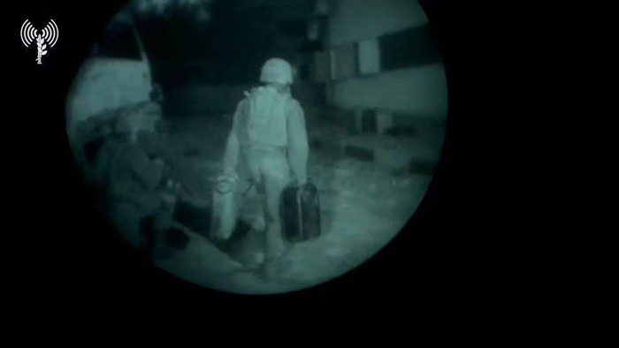 An Israeli army soldier walks towards a building structure carrying gallon containers, as they say, while delivering fuel to Al Shifa hospital, in a location given as Gaza, in this screengrab taken from a handout video released on November 12, 2023. Israeli Army/Handout via REUTERS Acquire Licensing Rights