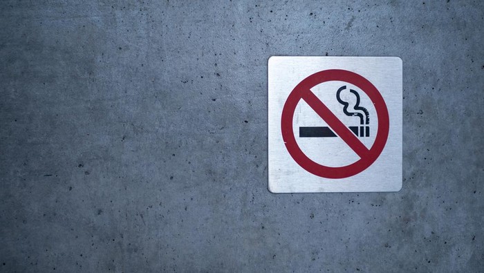 No smoking sign affixed to a wall on a building outside