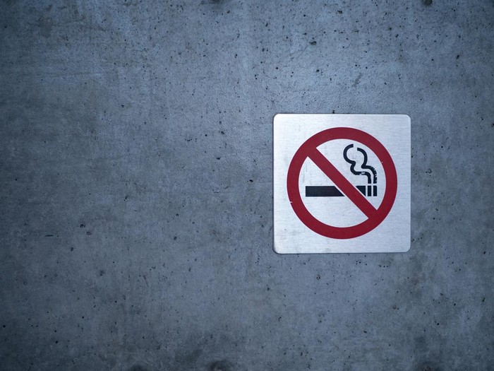 No smoking sign affixed to a wall on a building outside