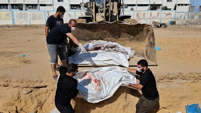Korban Kebrutalan Israel Dikubur Massal, Jenazah Diangkut Ekskavator A machinery transports unidentified bodies of Palestinians killed in Israeli strikes before they are buried in a mass grave, in the northern Gaza Strip November 11, 2023. REUTERS/Anas al-Shareef