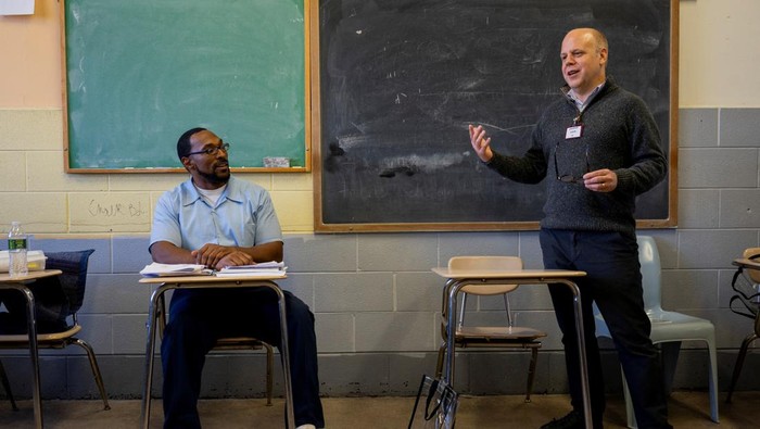 Marquis Harrison, passes paper to another prisoner, as they participate in classes as a part of the Northwestern Prison Education Program to earn their bachelor's degrees from Northwestern University at Stateville Correctional Center in Crest Hill, Illinois, U.S., November 13, 2023. REUTERS/Vincent Alban