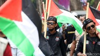 Sebagian peserta mengikuti aksi dengan mengibarkan bendera Palestina.