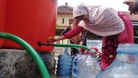 Warga sedang melakukan pengisian air bersih di tandon  yang telah diisi oleh  petugas BPBD Kota Blitar. Sebagian sumur warga debit airnya menyusut hingga harus mendapatkan bantuan.