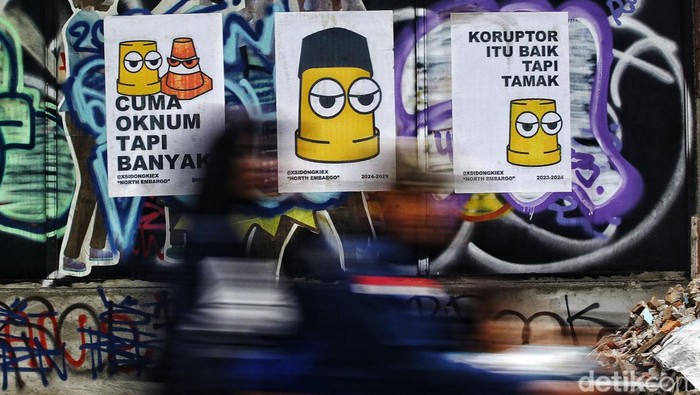 Warga melintas di depan mural bertemakan kritik sosial di beberapa titik di Jakarta Selata, Rabu (14/11/2023). Mural tersebut merupakan wujud ekspresi dari para seniman serta sebagai media penyampaian kritik sosial kepada pemerintah.