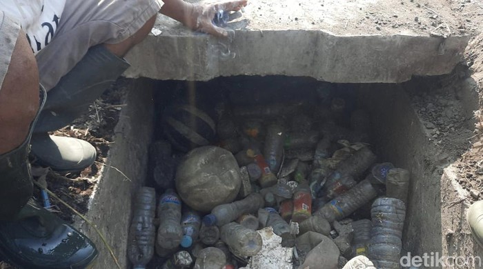 Petugas DCKPKP Gresik membersihkan sampah di saluran air