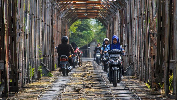 Foto udara pengendara melintas di jembatan Cincin Lama, Ngadipuro, Tuban, Jawa Timur, Rabu (15/11/2023).  Jembatan bekas rel kereta api peninggalan Belanda yang rusak itu masih digunakan warga setempat untuk menyebrangi sungai Bengawan Solo dari Kabupaten Tuban ke Kabupaten Lamongan. ANTARA FOTO/Muhammad Mada/nym.