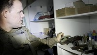 Seorang perwira Israel menunjukkan senapan yang menurutnya ditemukan di dalam tas yang disimpan di lemari berisi perbekalan medis di kompleks rumah sakit Al Shifa, di tengah operasi darat militer Israel melawan kelompok Islam Palestina Hamas, di Kota Gaza, 15 November 2023, dalam gambar diam ini diambil dari video.  