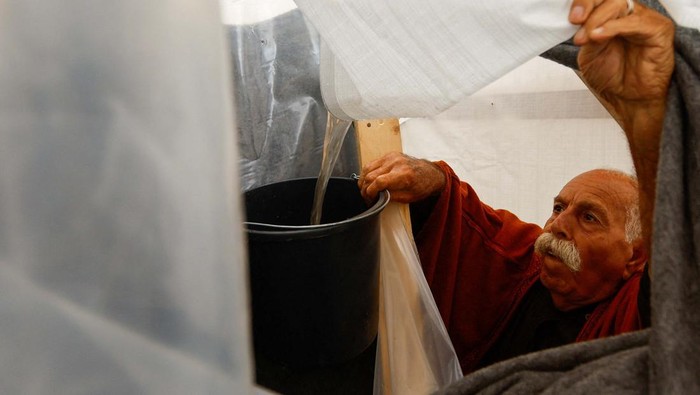 Momen Warga Gaza Tampung Air Hujan Displaced Palestinians sheltering in a tent camp collect rainwater, due to the lack of drinking water, following a rainfall, as the conflict between Israel and Palestinian Islamist group Hamas continues, in Khan Younis in the southern Gaza Strip, November 15, 2023. REUTERS/Ibraheem Abu Mustafa