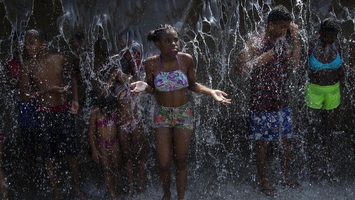 People cool off in a water fountain at Madureira Park amid a heat wave in Rio de Janeiro, Brazil, Wednesday, Nov. 15, 2023. (AP Photo/Bruna Prado)