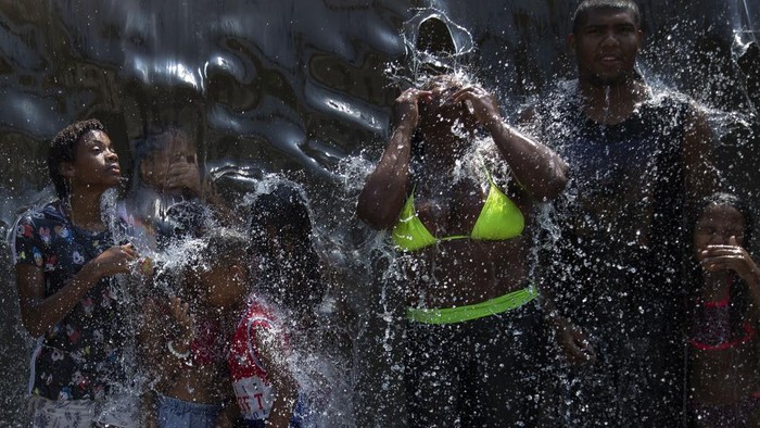 People cool off in a water fountain at Madureira Park amid a heat wave in Rio de Janeiro, Brazil, Wednesday, Nov. 15, 2023. (AP Photo/Bruna Prado)