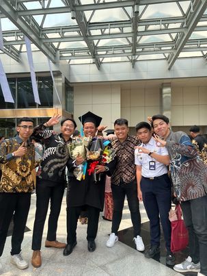Wisudawan diberikan buket nasi warteg oleh teman-temannya.