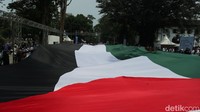 Sebuah bendera raksasa juga dikibarkan oleh massa aksi. Bendera raksasa itu dibawa oleh puluhan orang sebelum dibentangkan di tengah jalan. (Foto: Bima Bagaskara/detikJabar)