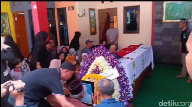 Ayah Yuda menangis sambil mencium foto putranya.