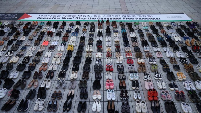 An activist places a floral tribute on a pair of shoes symbolising Palestinians killed, amid the conflict between Israel and Palestinian Islamist group Hamas, during a rally in solidarity of Palestinians in Seoul, South Korea, November 17, 2023.   REUTERS/Kim Hong-Ji