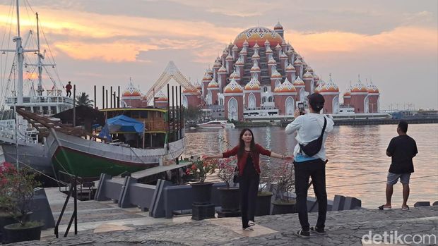 Spot foto dengan latar Masjid 99 Kubah yang diambil dari anjungan Pantai Losari.