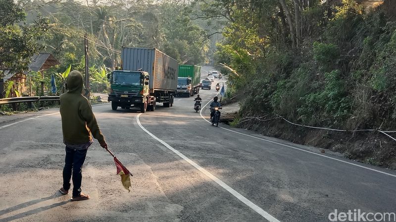 Relawan ketika memberi sinyal kepada truk yang hendak melintasi Tanjakan Kaljambe di Purworejo, Jumat (17/11/2023).