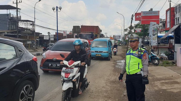 Polisi saat mengatur arus lalu lintas di tengah kemacetan di Jalan Poros Maros-Makassar.