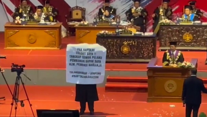 Seorang wisudawan Universitas Negeri Malang membentangkan spanduk minta tolong Kapolri agar pembunuh ayahnya ditangkap.