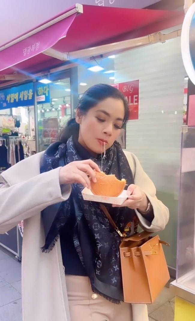 Titi saat menjajal street food di Korea. Memadukan warna hitam dan coklat untuk outfitnya, penampilan Titi terlihat menawan. Rambutnya pun terlihat simpel dengan hanya diikat satu ke belakang. Foto: Instagram/@titi_kamall