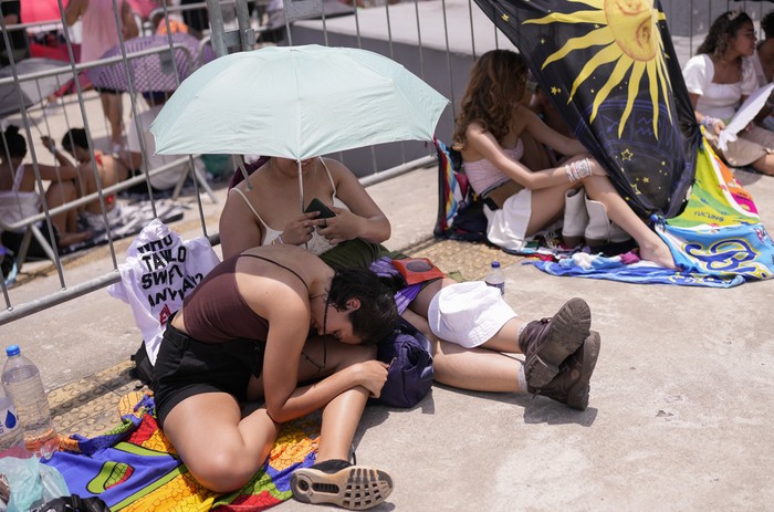 Taylor Swift fans wait for the doors of Nilton Santos Olympic stadium to open for her Eras Tour concert amid a heat wave in Rio de Janeiro, Brazil, Saturday, Nov. 18, 2023. A 23-year-old Taylor Swift fan died at the singer's Eras Tour concert in Rio de Janeiro Friday night, according to a statement from the show's organizers in Brazil.  (AP Photo/Silvia Izquierdo)