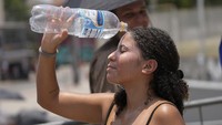 Seorang penonton bahkan menyiram wajahnya dengan air minum demi mengurangi rasa panas. Foto: AP/Silvia Izquierdo