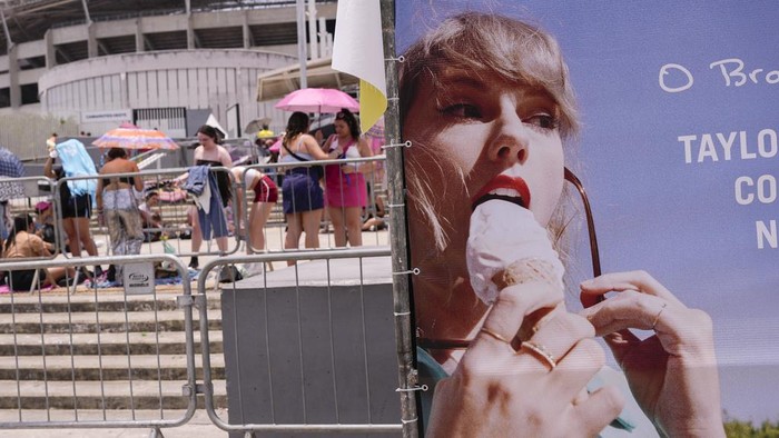 Taylor Swift fans wait for the doors of Nilton Santos Olympic stadium to open for her Eras Tour concert amid a heat wave in Rio de Janeiro, Brazil, Saturday, Nov. 18, 2023. A 23-year-old Taylor Swift fan died at the singer's Eras Tour concert in Rio de Janeiro Friday night, according to a statement from the show's organizers in Brazil.  (AP Photo/Silvia Izquierdo)