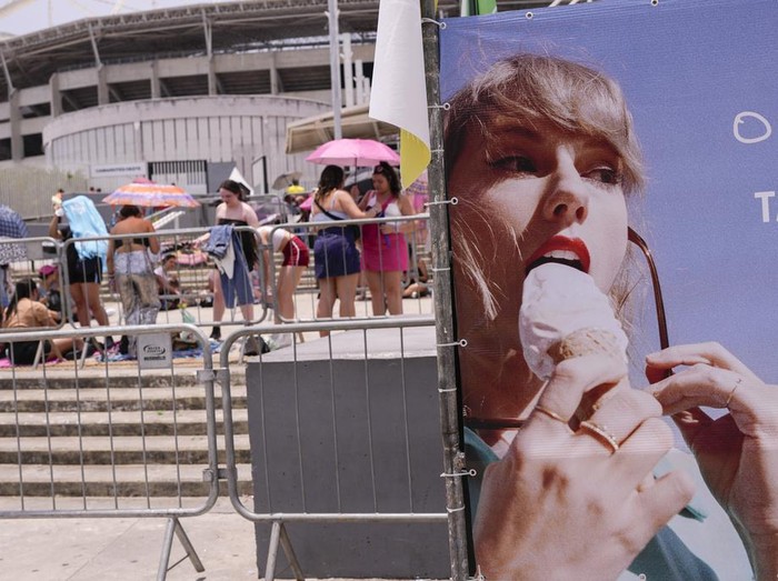 Taylor Swift fans wait for the doors of Nilton Santos Olympic stadium to open for her Eras Tour concert amid a heat wave in Rio de Janeiro, Brazil, Saturday, Nov. 18, 2023. A 23-year-old Taylor Swift fan died at the singers Eras Tour concert in Rio de Janeiro Friday night, according to a statement from the shows organizers in Brazil.  (AP Photo/Silvia Izquierdo)