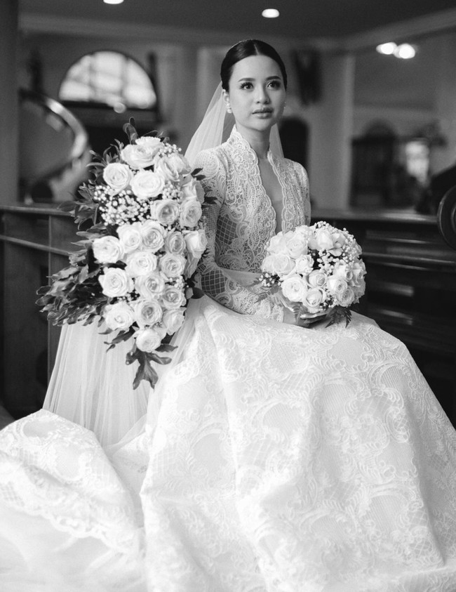 Mengenakan gaun pengantin panjang putih rancangan desainer Hani Tio Han, Anggi terlihat cantik dan anggun. Gaun pengantin tersebut terlihat simpel namun elegan dengan dipenuhi brukat. Foto: Instagram/@anggimarito