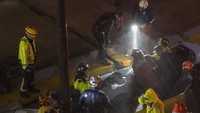Tim penyelamat sedang mengevakuasi korban dari dalam mobil yang tertimpa dinding terowongan. 
