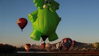 Beragam balon udara dengan bentuk bentuk soda, hewan, dan boneka menghias udara.  