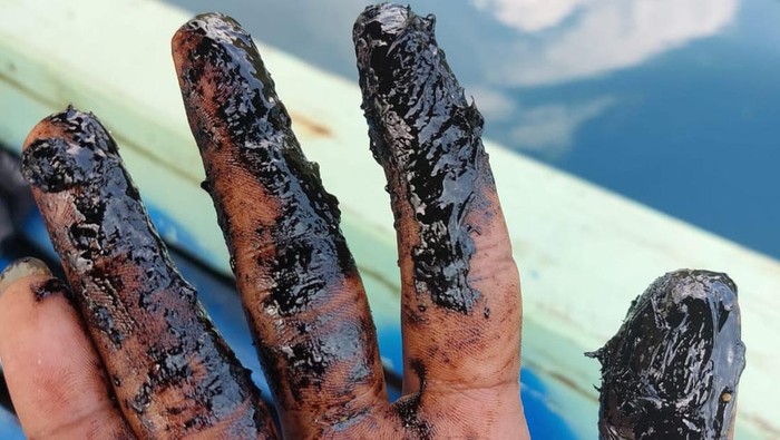 Nelayan menunjukkan oli yang diduga mencemari laut di Halmahera Timur, Maluku Utara.