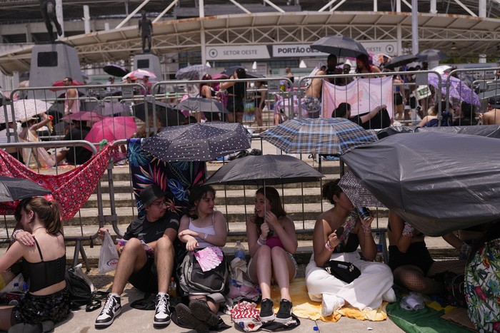 Taylor Swift fans wait for the doors of Nilton Santos Olympic stadium to open for her Eras Tour concert amid a heat wave in Rio de Janeiro, Brazil, Saturday, Nov. 18, 2023. A 23-year-old Taylor Swift fan died at the singer's Eras Tour concert in Rio de Janeiro Friday night, according to a statement from the show's organizers in Brazil.  (AP Photo/Silvia Izquierdo)