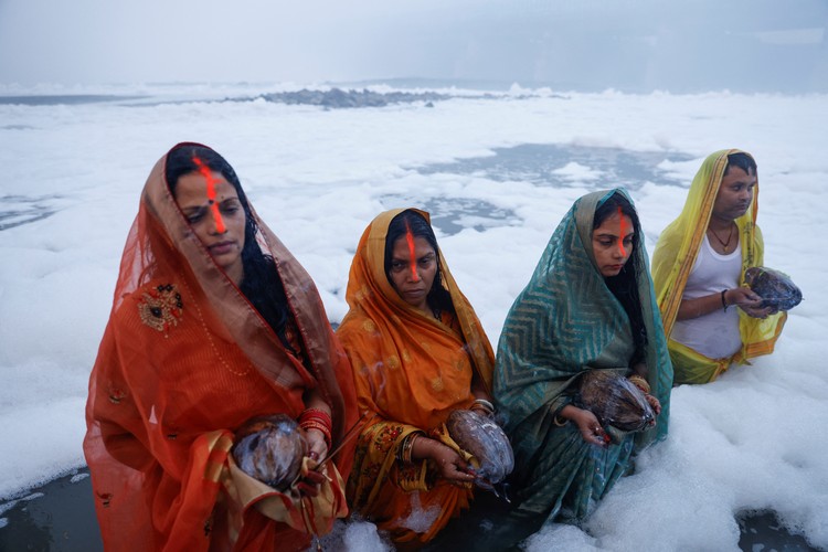 Potret Warga India Gelar Ritual di Sungai Penuh Limbah Beracun Hindu devotees worship the Sun god as they stand amidst the foam covering the polluted Yamuna river during the Hindu religious festival of Chhath Puja on a smoggy morning in New Delhi, India, November 20, 2023. REUTERS/Anushree Fadnavis TPX IMAGES OF THE DAY